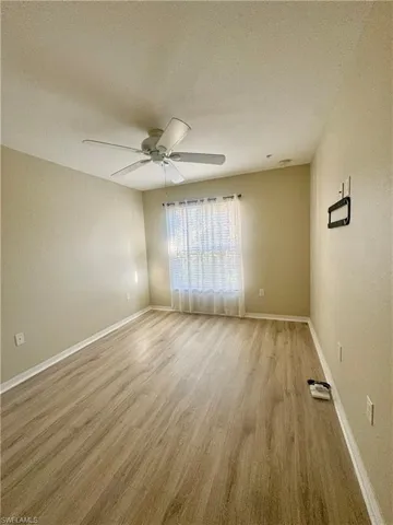 Empty room featuring a textured ceiling, light wood-style flooring, and a textured wall