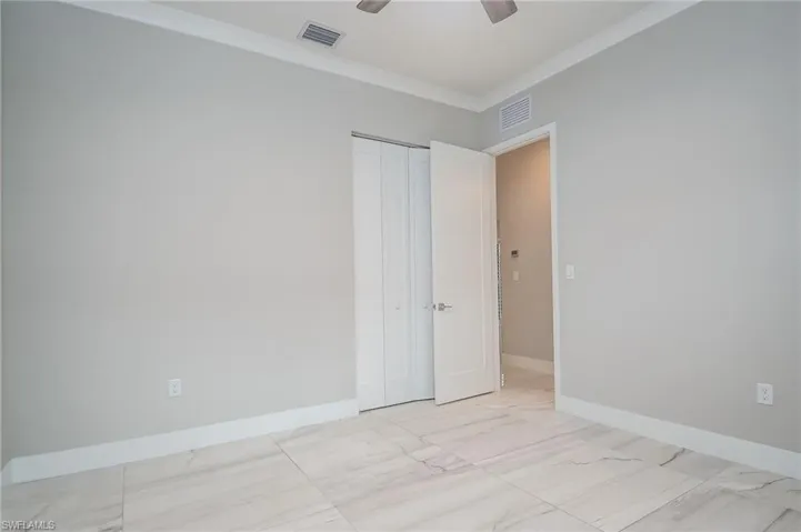 room with crown molding, light marble finish flooring, and ceiling fan