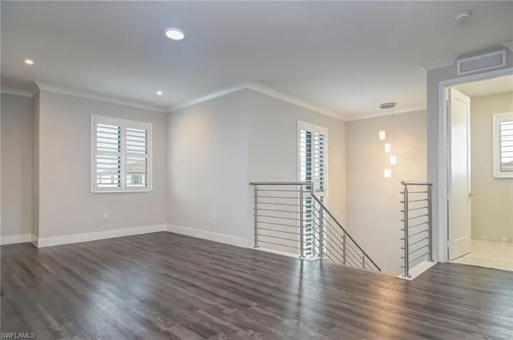Spare room featuring crown molding, dark wood-style floors, and recessed lighting