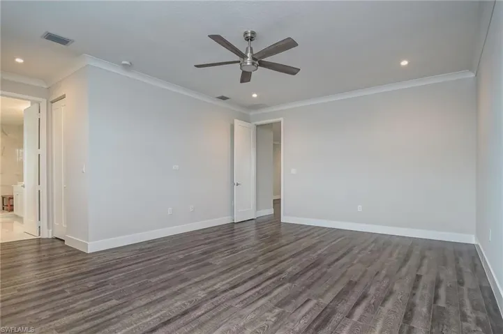 Spare room featuring ornamental molding, ceiling fan, dark wood finished floors, and recessed lighting