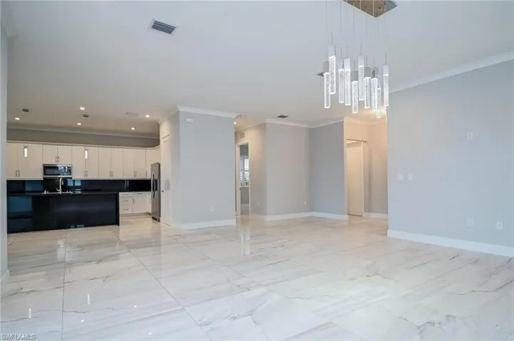 Unfurnished living room featuring crown molding, light marble finish floors, and recessed lighting