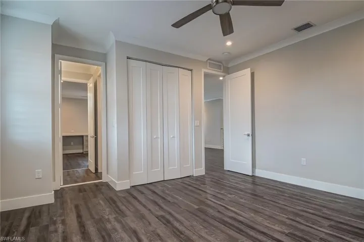 Unfurnished bedroom featuring ornamental molding, dark wood finished floors, a closet, a ceiling fan, and recessed lighting