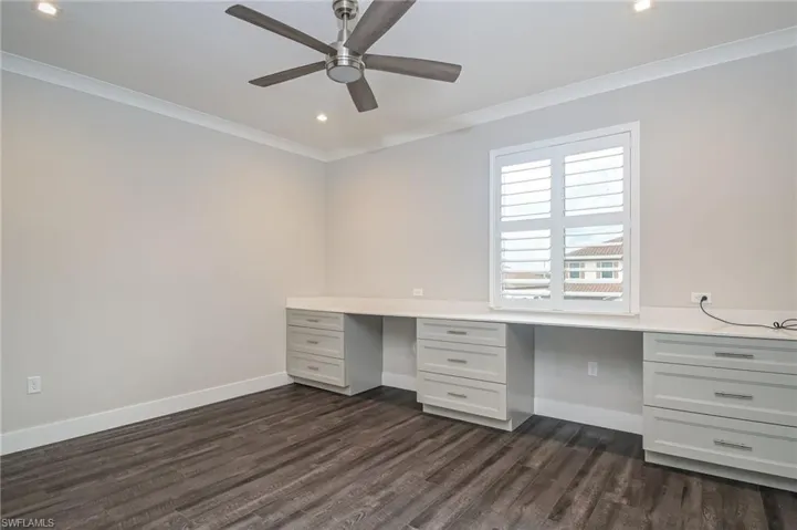 Unfurnished office with ornamental molding, recessed lighting, dark wood-type flooring, built in desk, and a ceiling fan