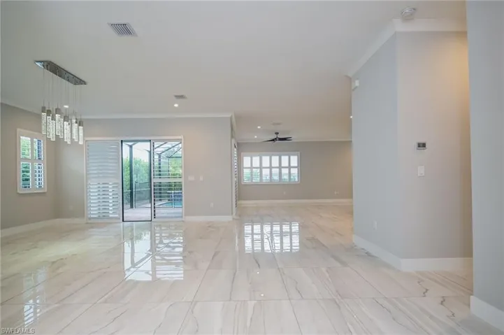 Empty room featuring a chandelier, a ceiling fan, crown molding, and light marble finish flooring