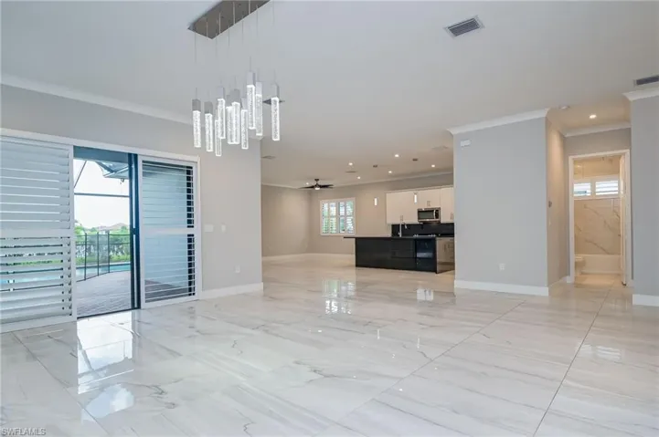 Unfurnished living room with crown molding, ceiling fan, and light marble finish flooring