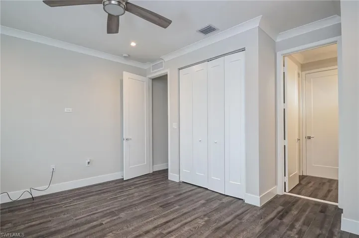 Unfurnished bedroom with crown molding, a closet, dark wood finished floors, recessed lighting, and a ceiling fan