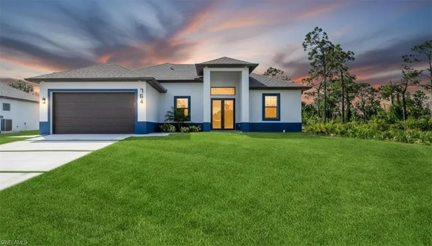 Prairie-style home featuring a lawn, driveway, stucco siding, an attached garage, and a shingled roof