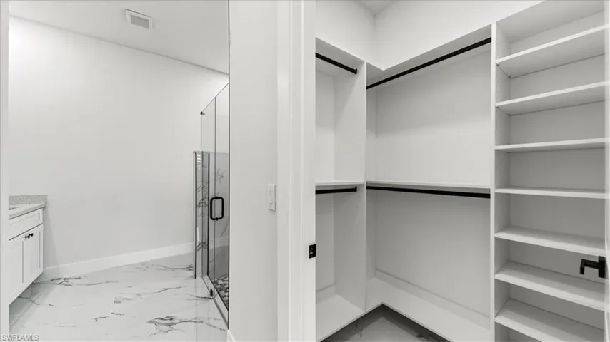 Spacious closet featuring light marble finish flooring