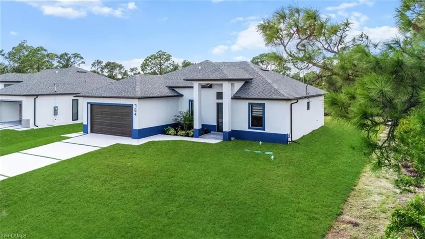 View of front of property with a front lawn, stucco siding, an attached garage, and roof with shingles