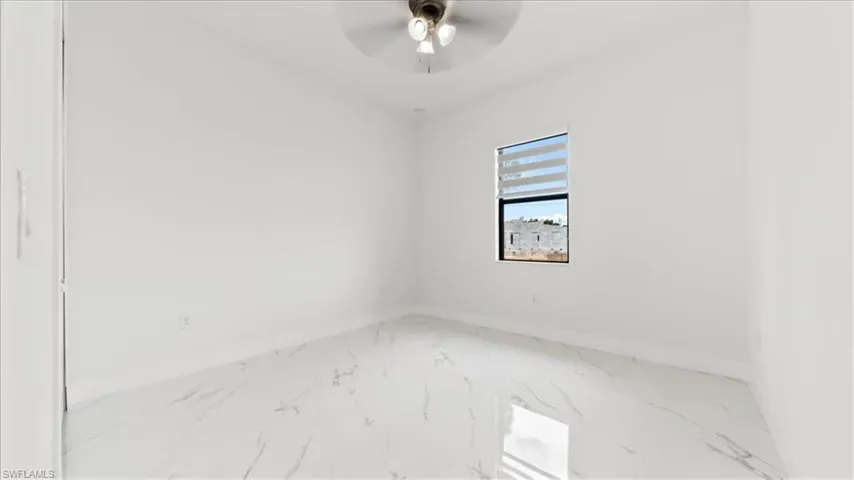 Empty room with marble look tiles and a ceiling fan
