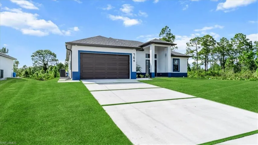 Prairie-style house with stucco siding, a front lawn, driveway, and a garage