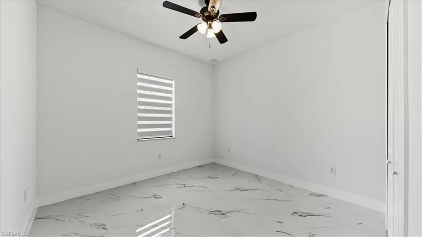 Unfurnished room featuring light marble finish floors and ceiling fan