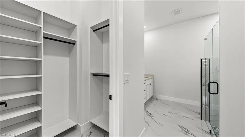 Spacious closet featuring light marble finish floors