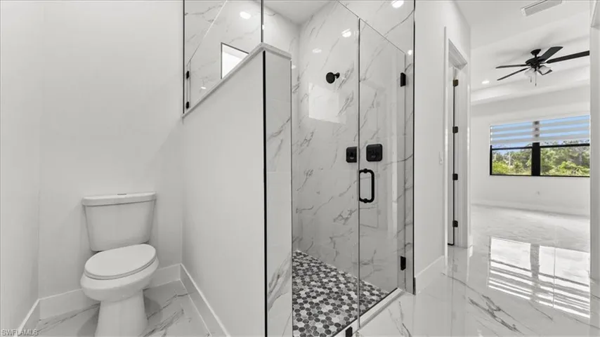 Bathroom with marble finish flooring, a marble finish shower, and a ceiling fan