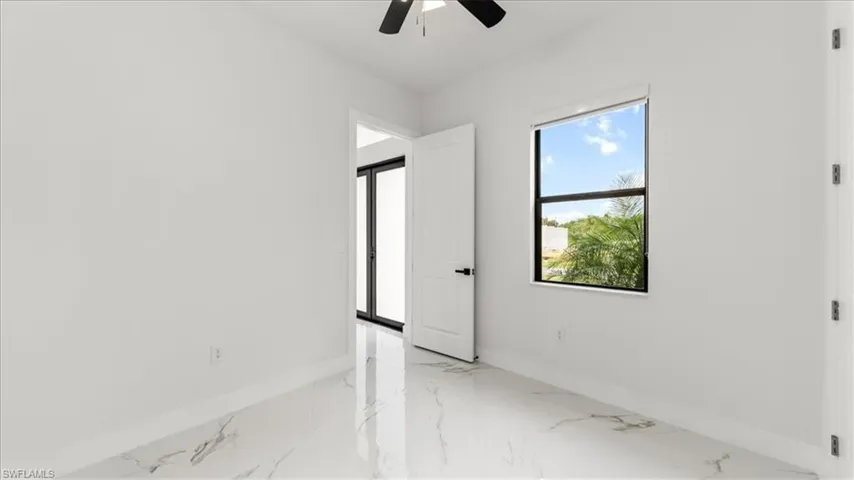 Spare room featuring light marble finish floors and a ceiling fan