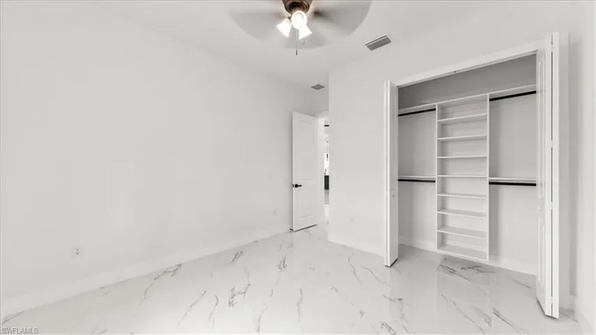 Unfurnished bedroom with light marble finish floors, a closet, and ceiling fan