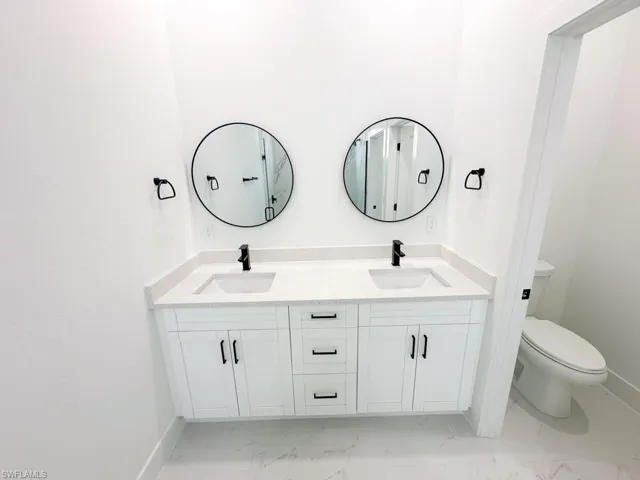 Bathroom with double vanity, toilet, and tile floors