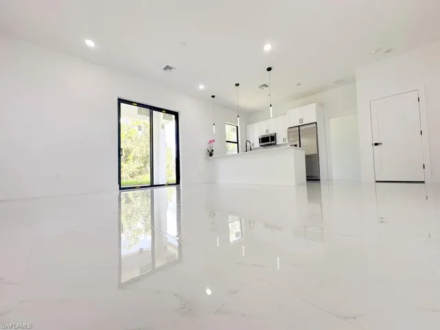 Kitchen with decorative light fixtures, stainless steel appliances, white cabinetry, sink, and light tile floors