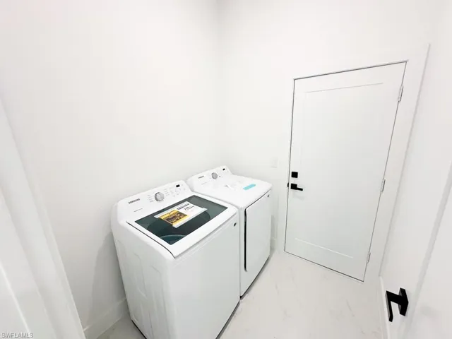 Clothes washing area with separate washer and dryer and light tile flooring