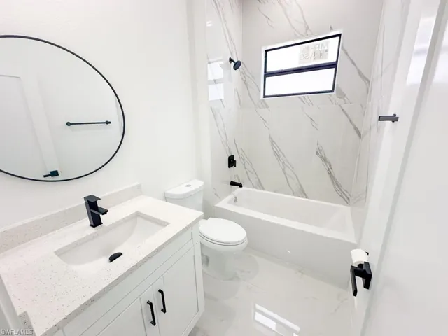 Full bathroom featuring vanity with extensive cabinet space, tile flooring, toilet, and tiled shower / bath combo