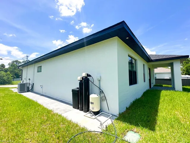 View of property exterior featuring central AC and a lawn