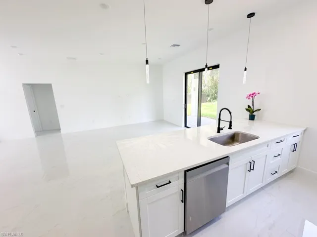 Kitchen with sink, dishwasher, white cabinets, and light tile floors