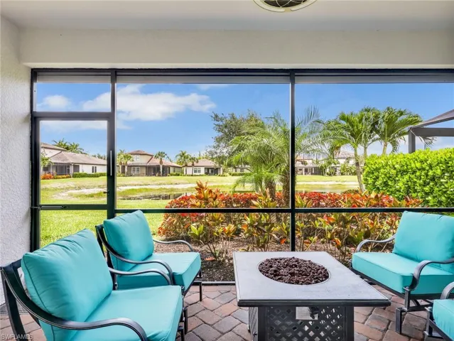 Living Room with Sliders Leading to the Screened In Lanai with Lake View and Paver Lanai