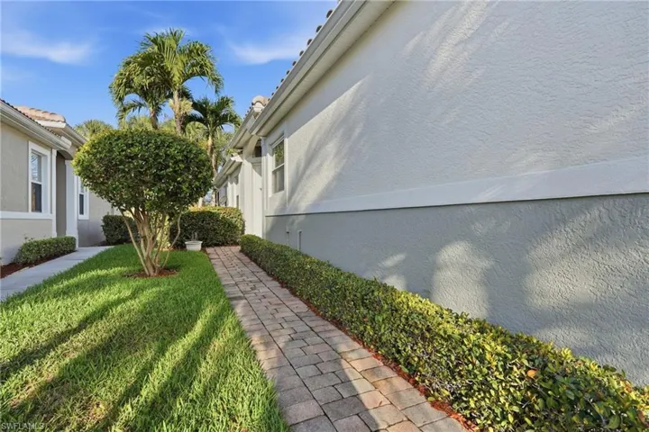 View of side of home featuring stucco siding and a yard - Virtually Edited Image