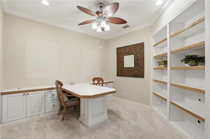 Office area with crown molding, light colored carpet, a ceiling fan, and built in shelves - Virtually Edited Image
