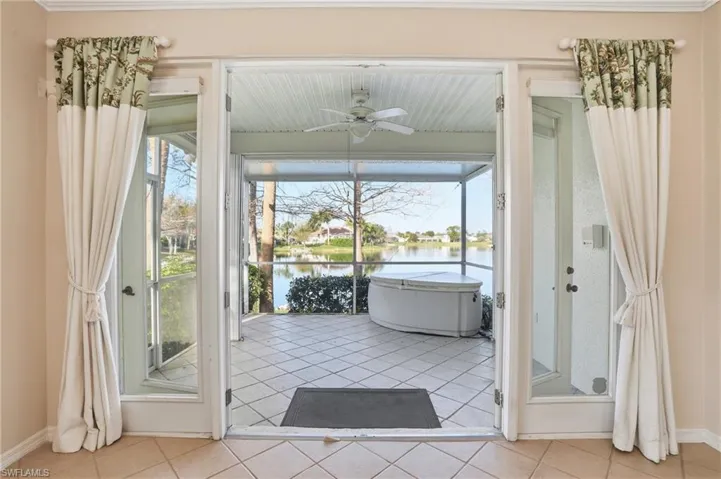 Doorway to outside with ceiling fan, a water view, and tile patterned floors - Virtually Edited Image