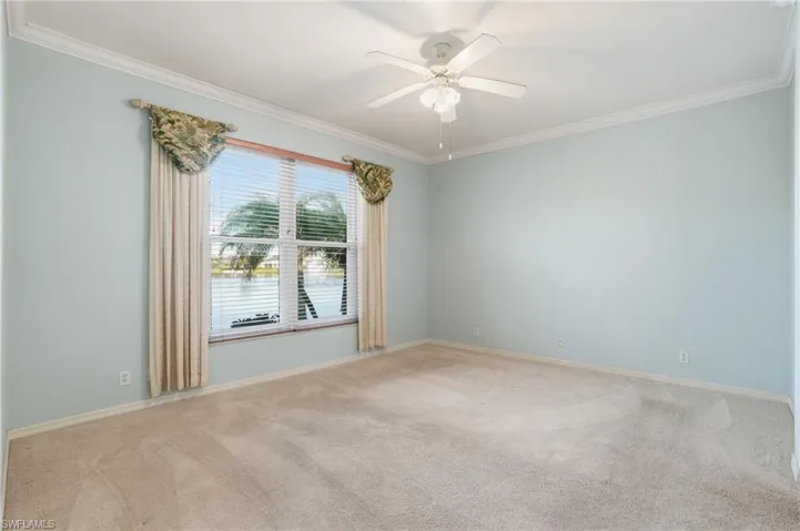 Unfurnished room with light carpet, ornamental molding, ceiling fan, and a water view - Virtually Edited Image