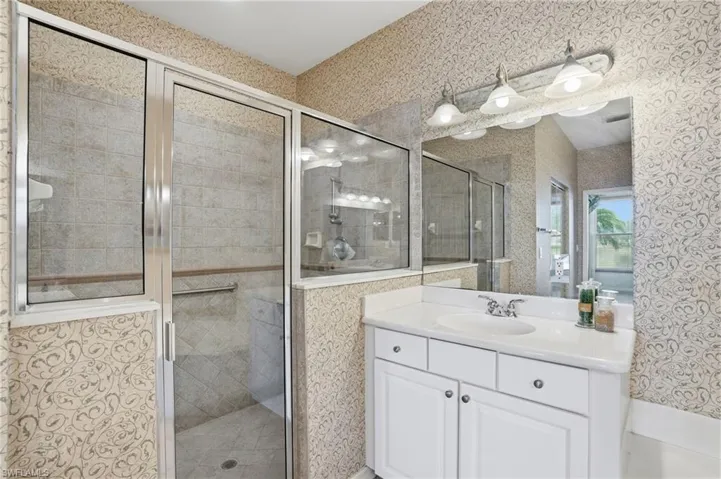 Full bathroom with wallpapered walls, vanity, and a shower stall - Virtually Edited Image