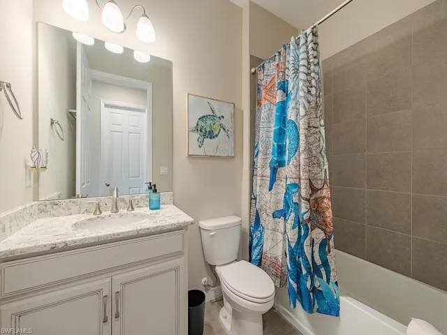 Full bathroom featuring shower / bathtub combination with curtain, toilet, and vanity