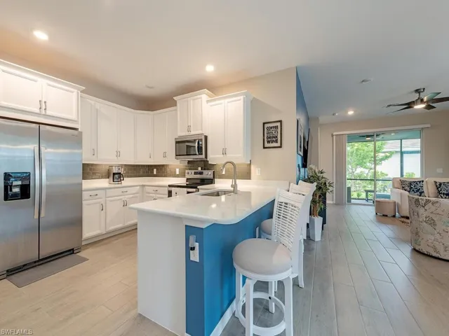 Kitchen with appliances with stainless steel finishes, sink, kitchen peninsula, backsplash, and ceiling fan