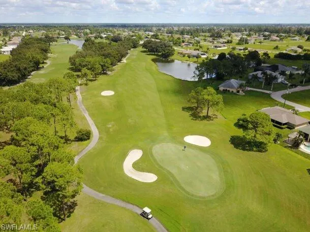 Aerial perspective of suburban area with a large body of water, a golf course, and a tree filled landscape