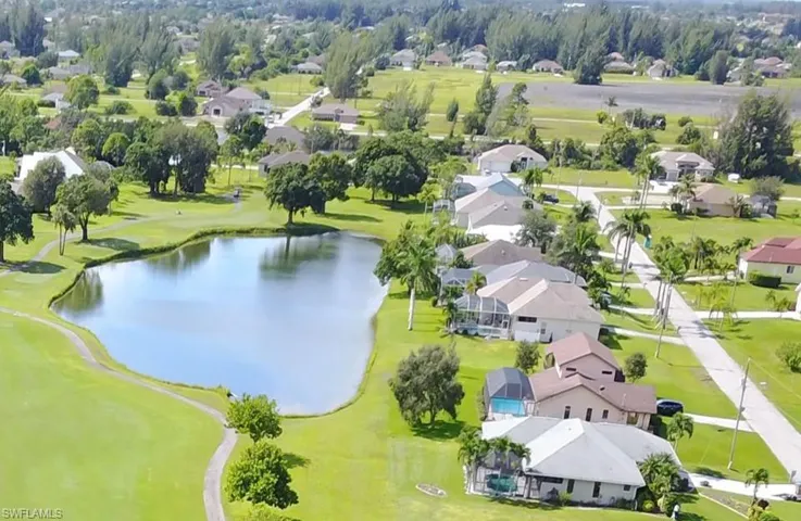 Aerial view of residential area featuring a nearby body of water and a golf club