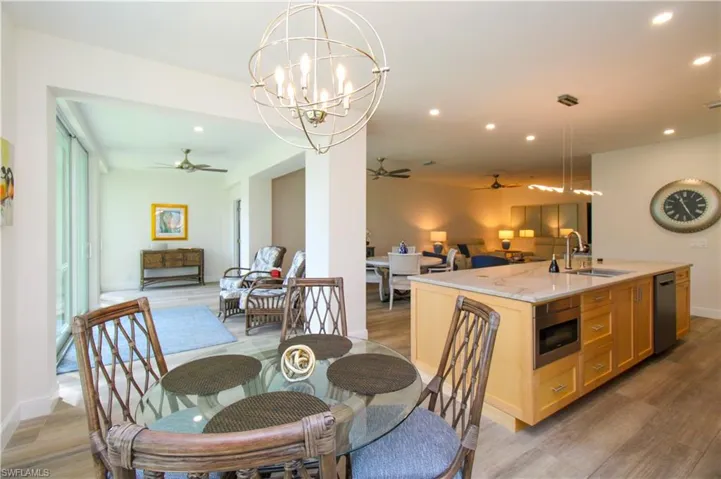 Dining space featuring sink, light hardwood / wood-style flooring, and ceiling fan with notable chandelier