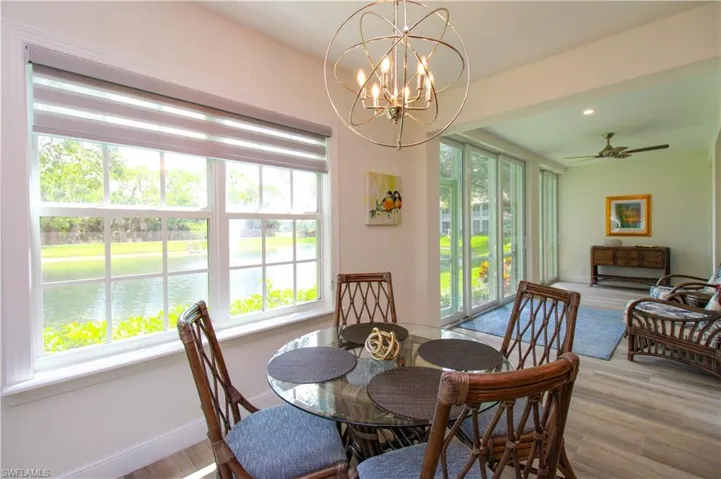 Dining area with a wealth of natural light, hardwood / wood-style floors, a water view, and ceiling fan with notable chandelier