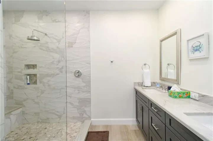 Bathroom with a shower with shower door, dual vanity, and hardwood / wood-style flooring