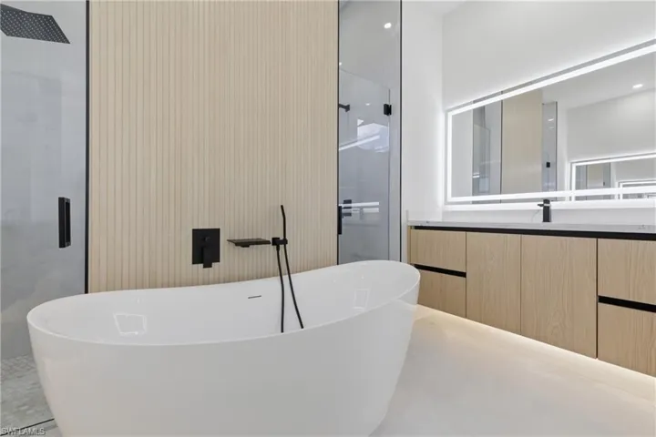 Full bath featuring vanity, a freestanding bath, and recessed lighting