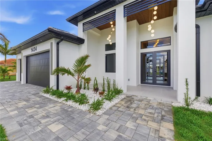 Property entrance featuring stucco siding, french doors, a garage, and decorative driveway