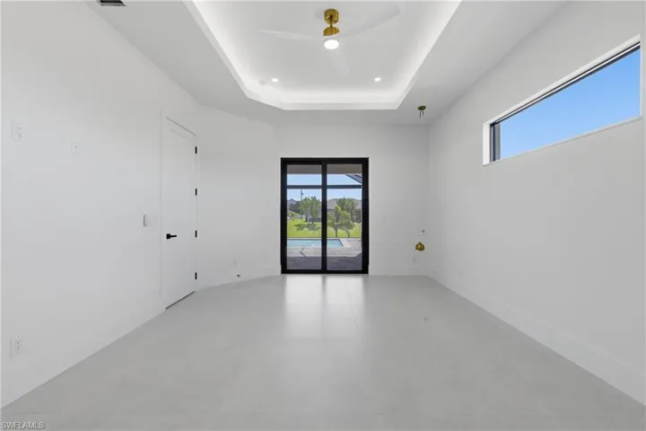 Unfurnished room featuring ceiling fan, healthy amount of natural light, a raised ceiling, and recessed lighting