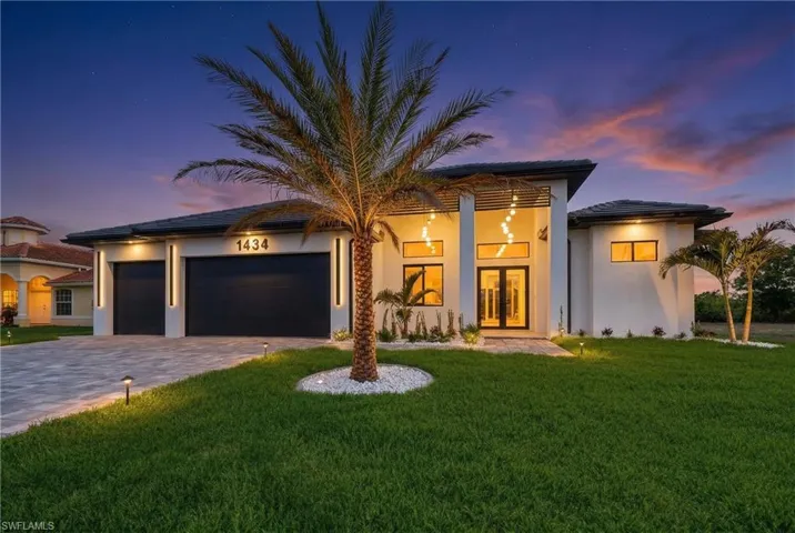 View of front of house with a lawn, a garage, decorative driveway, stucco siding, and french doors
