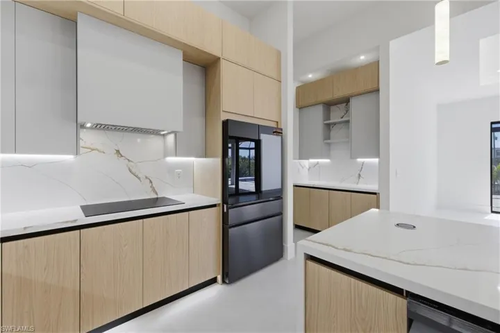 Kitchen featuring modern cabinets, light stone counters, tasteful backsplash, and open shelves
