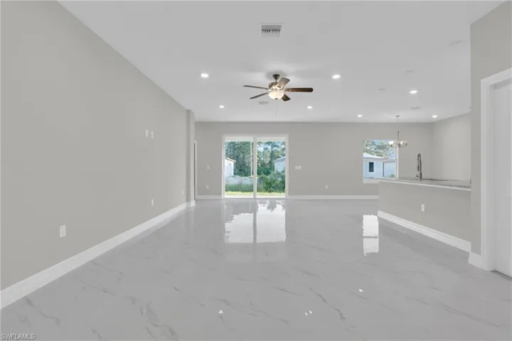 Unfurnished room with a ceiling fan, hanging lights, and light marble finish flooring