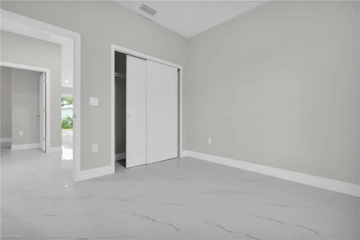 Unfurnished bedroom with light marble finish flooring and a closet