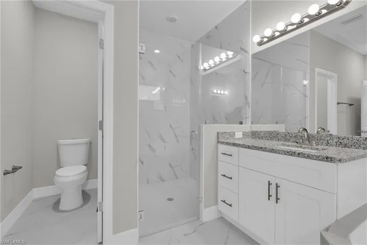 Bathroom with a marble finish shower, vanity, and light marble finish flooring