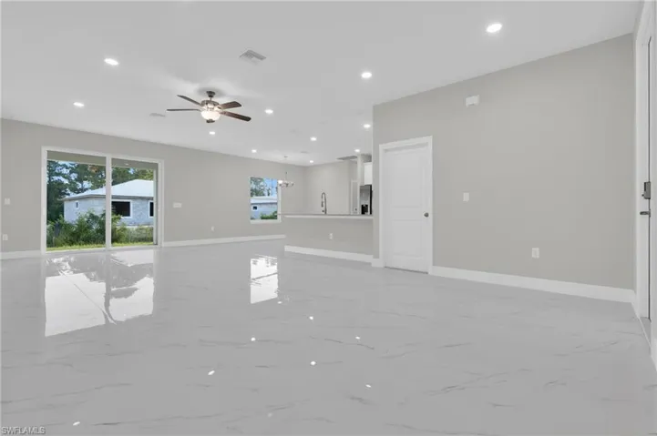 Unfurnished living room featuring a ceiling fan, light marble finish flooring, and hanging lights
