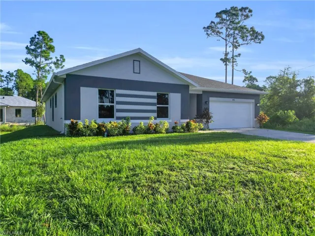 Ranch-style home featuring an attached garage, stucco siding, a front lawn, and driveway