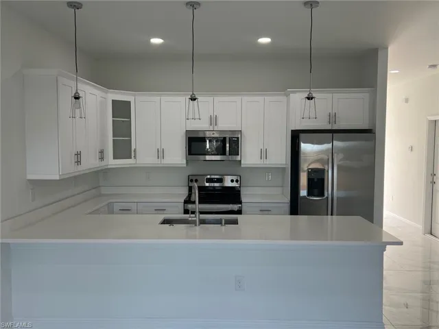 Kitchen with light tile patterned flooring, stainless steel appliances, and decorative light fixtures